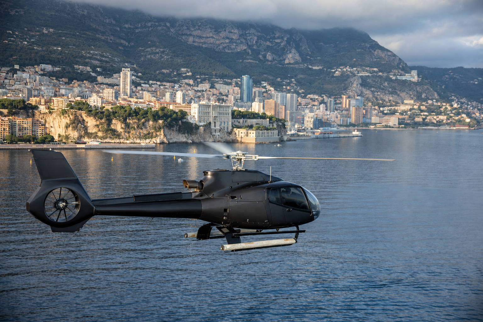 Helicopter on a coastal heliport above Monaco harbour at dusk
