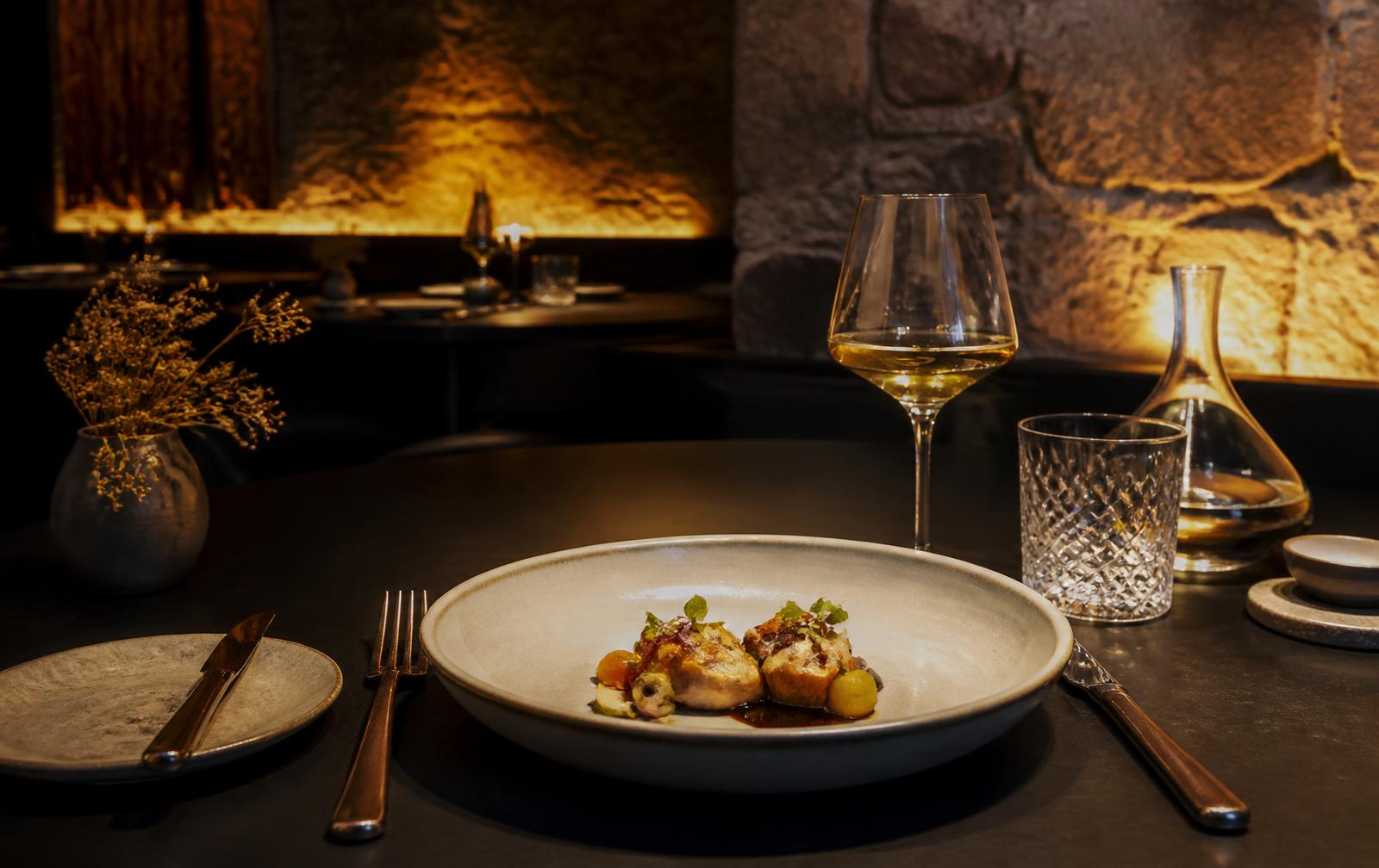 Fine dining table set in a warmly lit stone-walled restaurant
