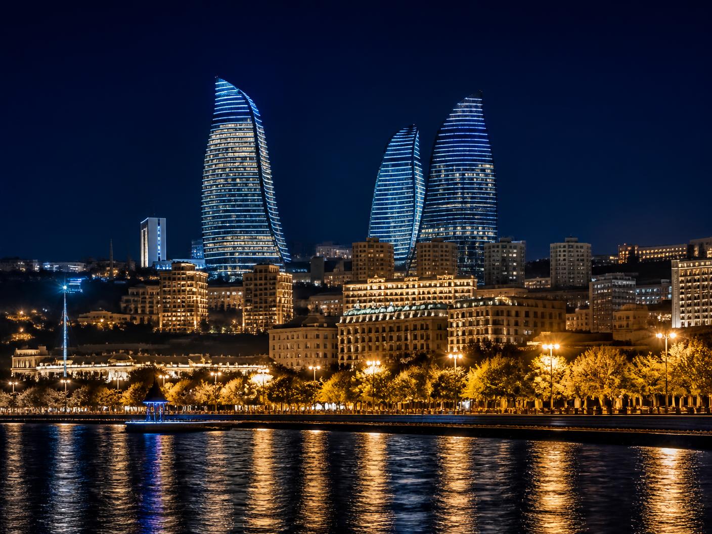 Modern Baku skyline at night with illuminated curved glass towers above the waterfront