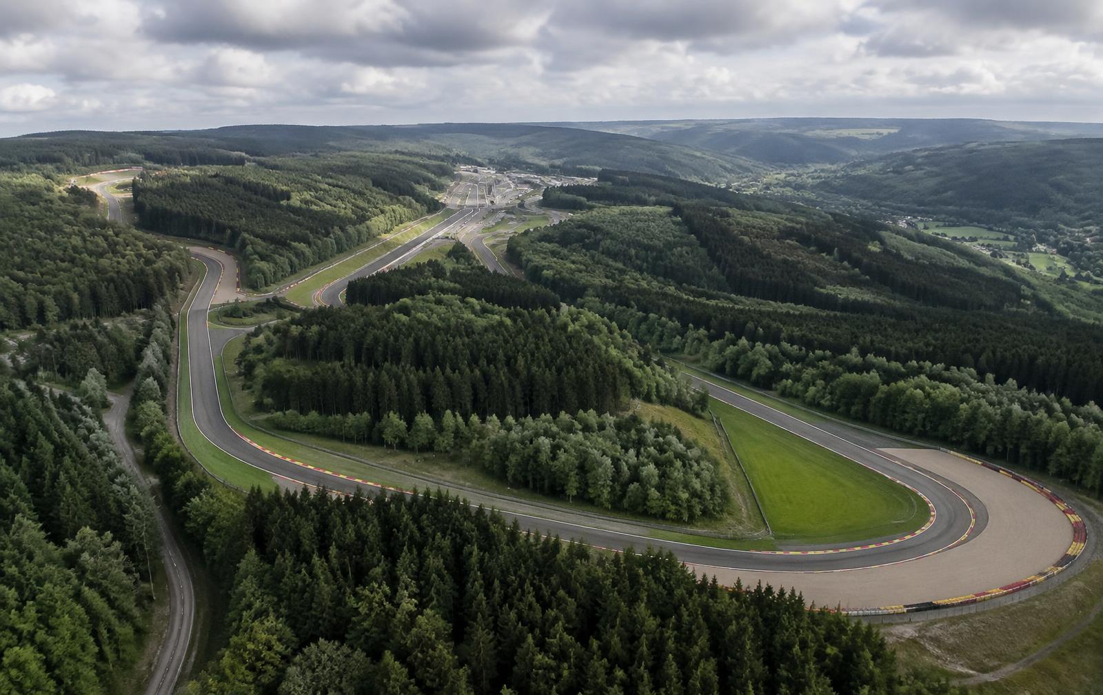 Aerial view of a long racing circuit winding through forested Ardennes hills
