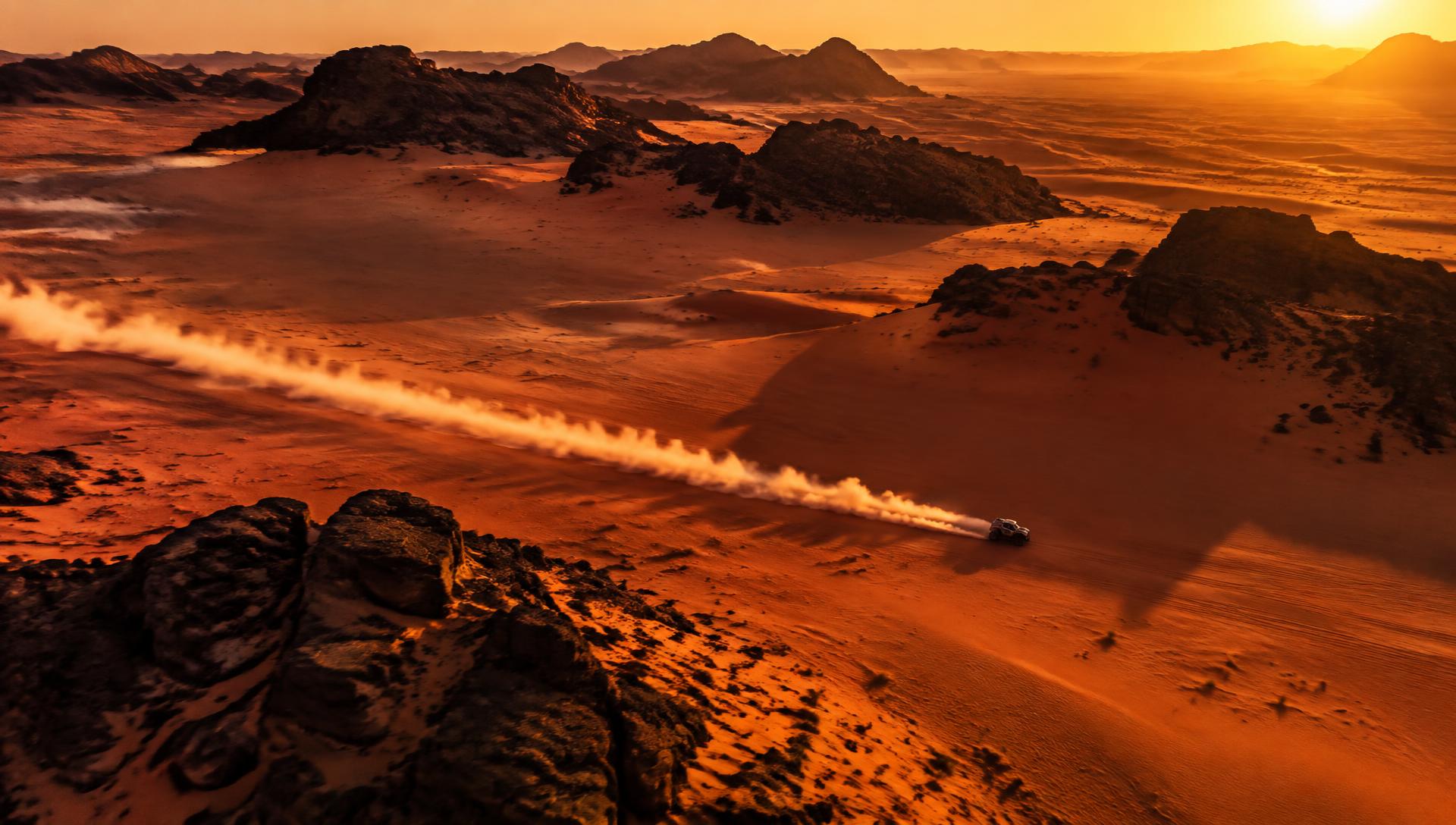 Rally raid vehicle crossing Saudi desert dunes at sunset