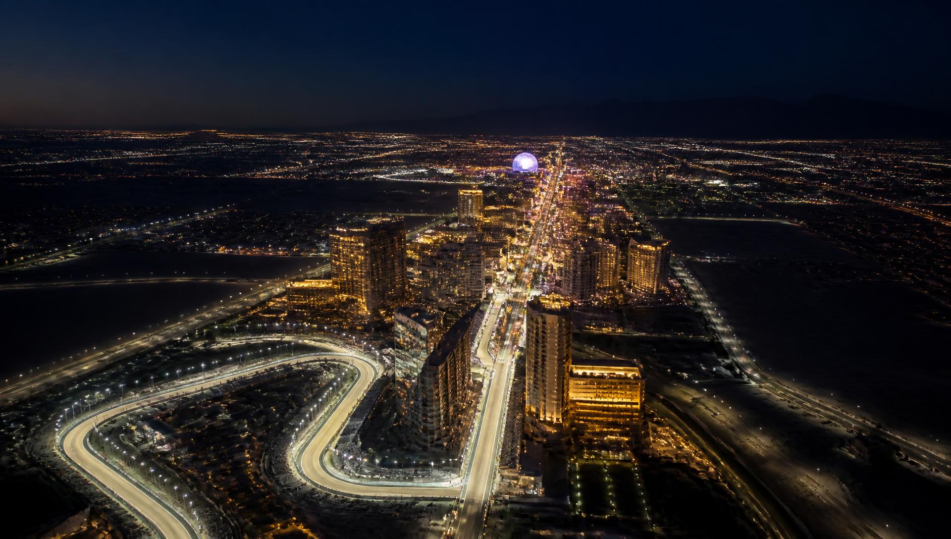 Aerial night view of an illuminated desert city boulevard with a floodlit street circuit