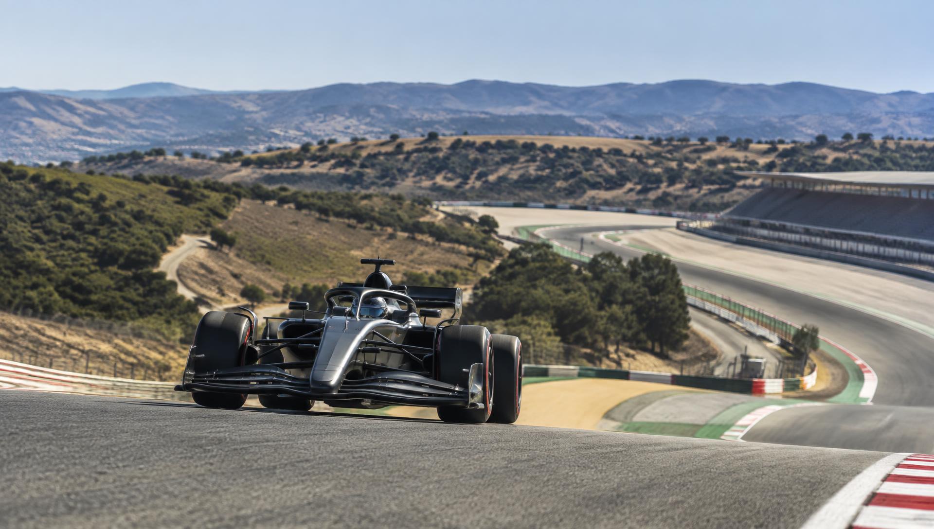 Monolugar de Fórmula 1 a passar o topo de uma subida num circuito ao sol