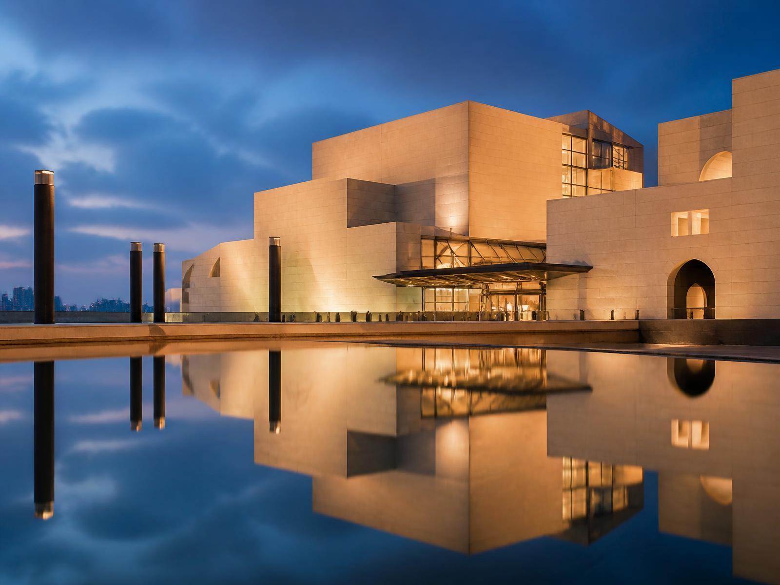 Contemporary limestone museum architecture reflected in calm water at dusk