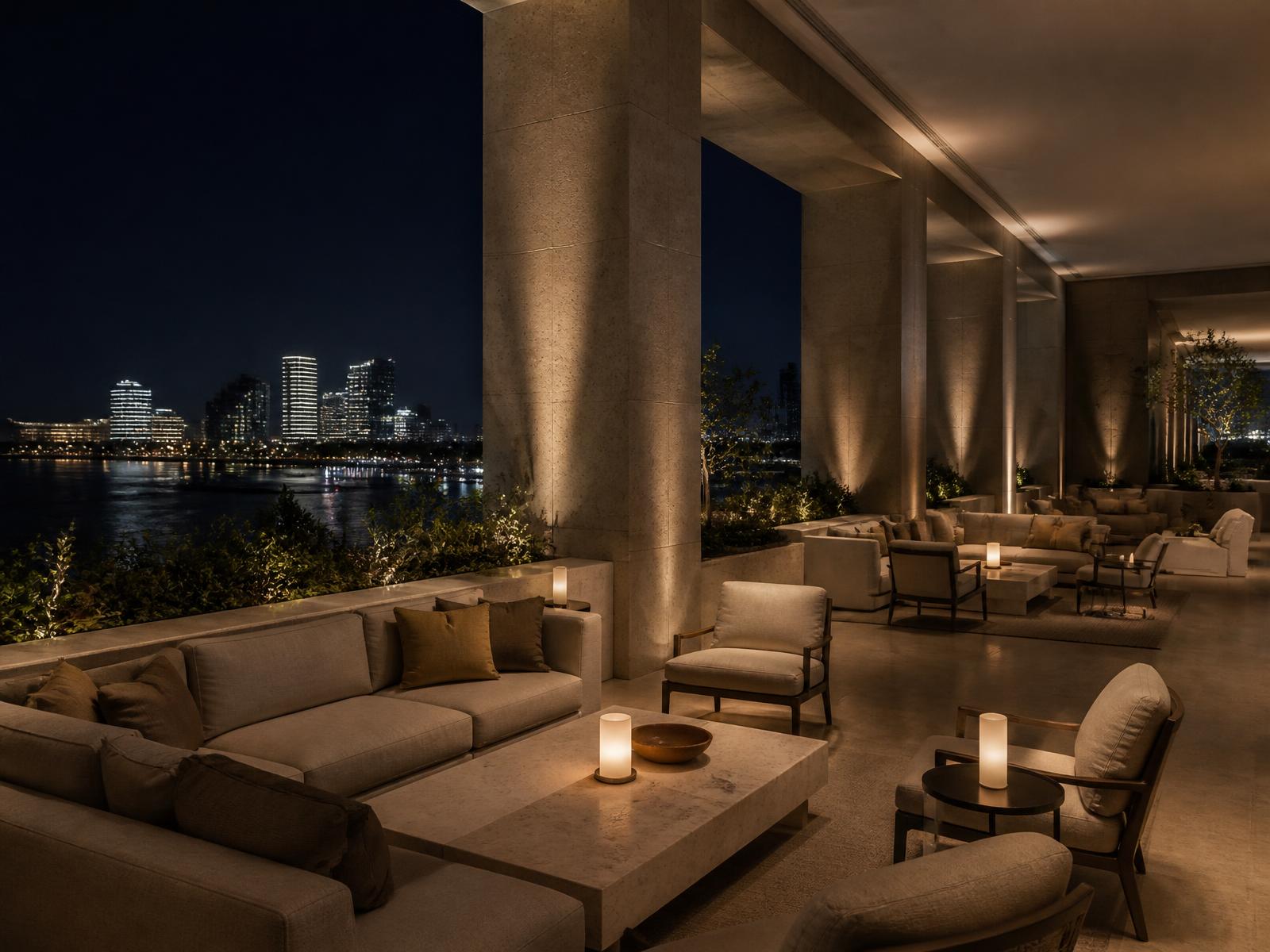 Quiet luxury hotel lounge terrace at night above a modern waterfront