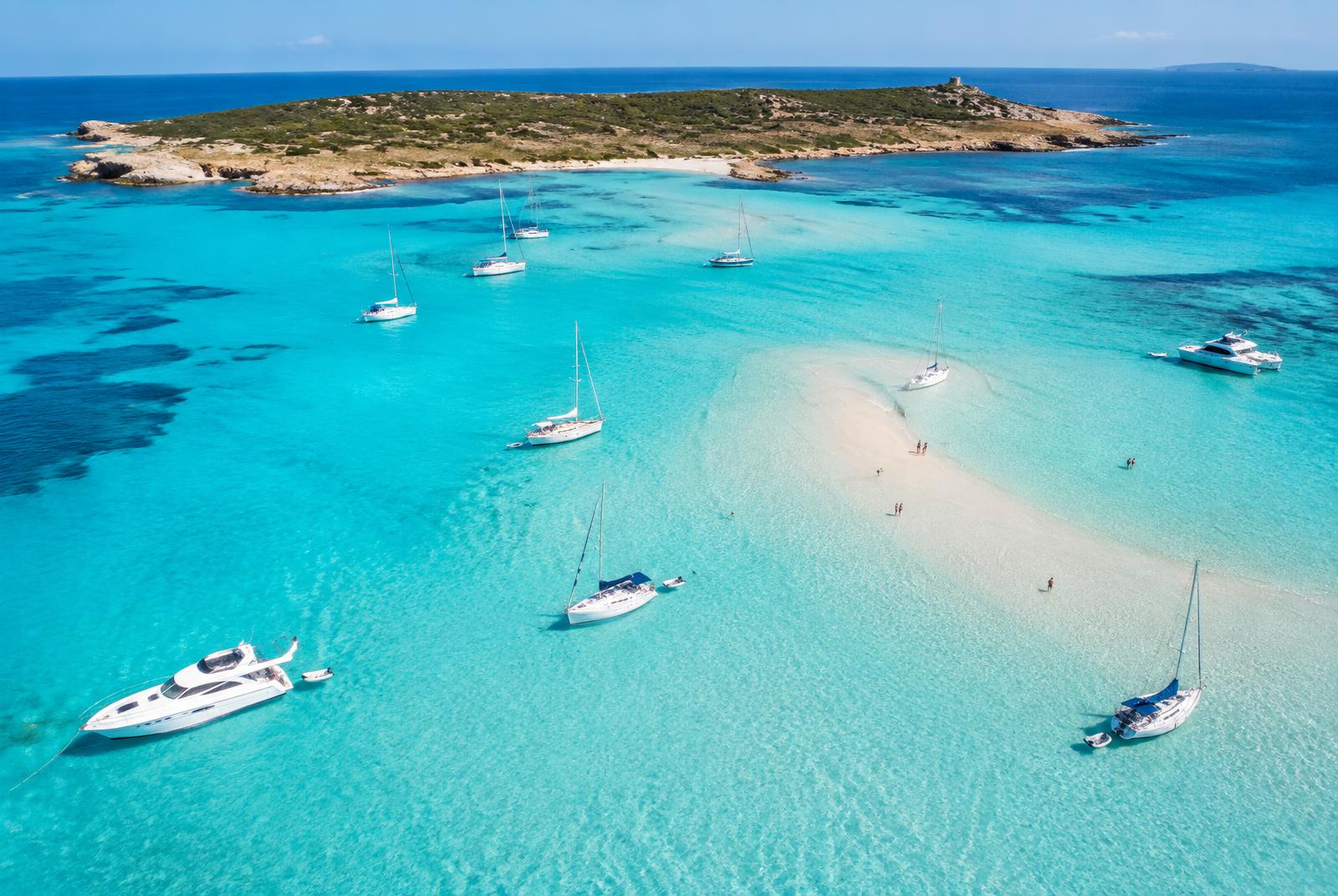 Yacht anchored in a sheltered limestone cala on the south coast of Menorca